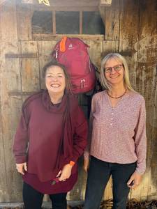 Zwei Frauen vor Scheunentor, Rucksack im Hintergrund