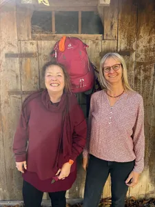 Zwei Frauen vor Scheunentor, Rucksack im Hintergrund